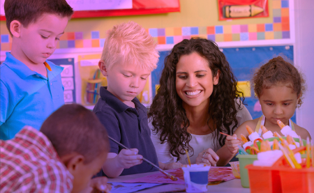 Image: Teacher assisting joyful students. Depicts how charter schools can gain a competitive advantage