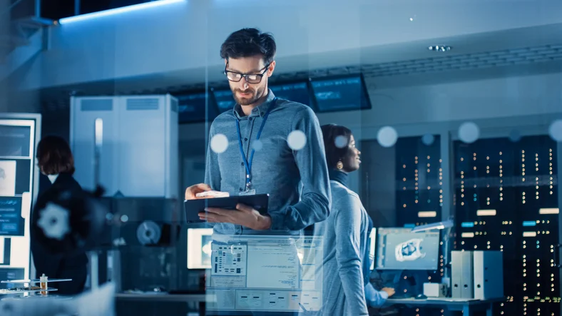 A man in a datacenter, monitoring a computer screen while managing IT infrastructure tasks