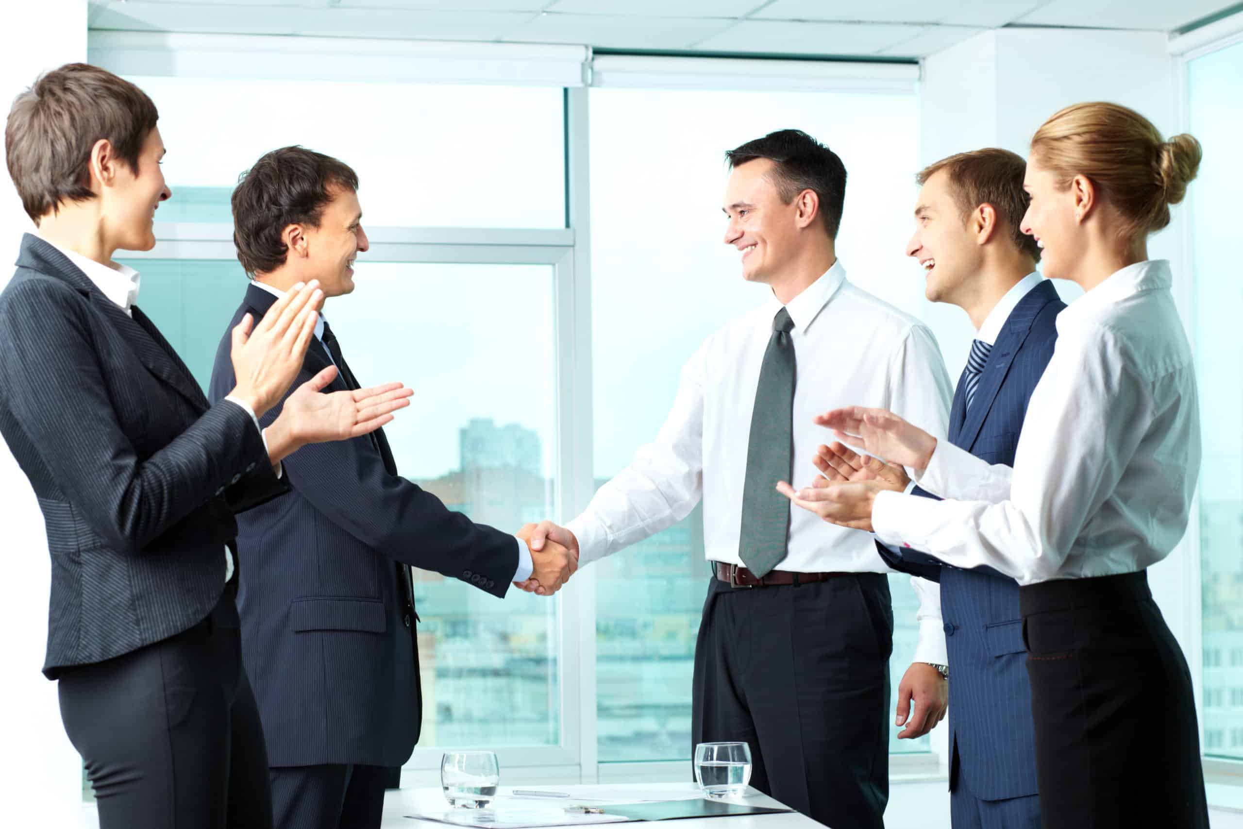 Business professionals shaking hands in an office setting, symbolizing partnership and collaboration