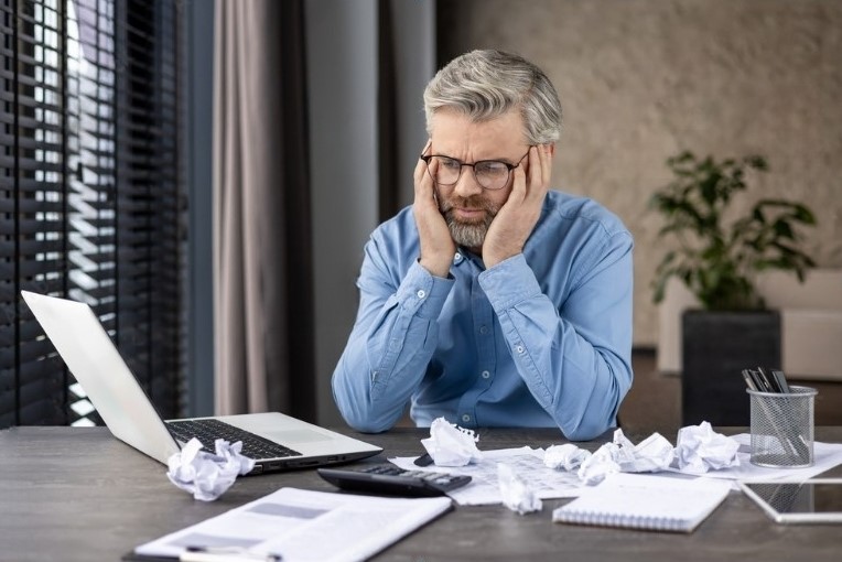 Concerned man in office analyzing business reports, reflecting key managed IT issues CFOs need help with. 